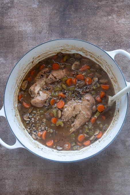 Finished chicken and wild rice soup in pot with chicken breasts whole.