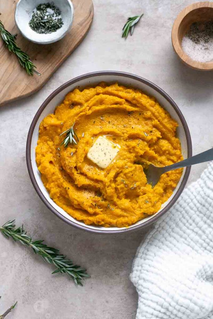 Mashed kabocha squash in a bowl with melted butter.