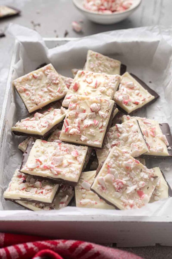 Peppermint bark squares stacked on each other in a serving box.
