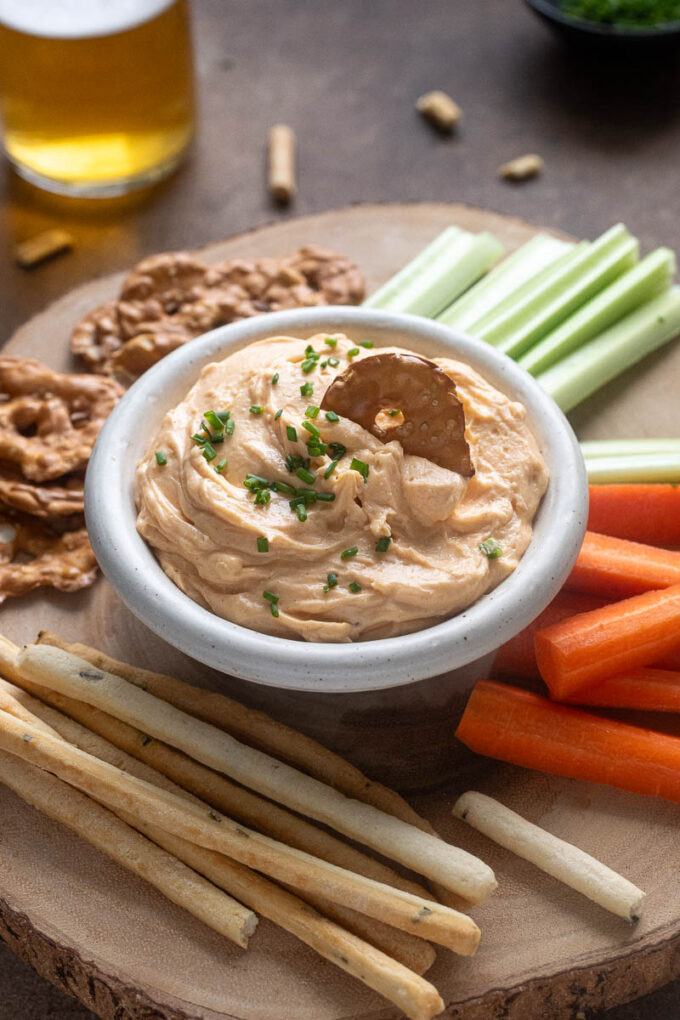 White cheddar pub cheese in a bowl with pretzel dipped in.