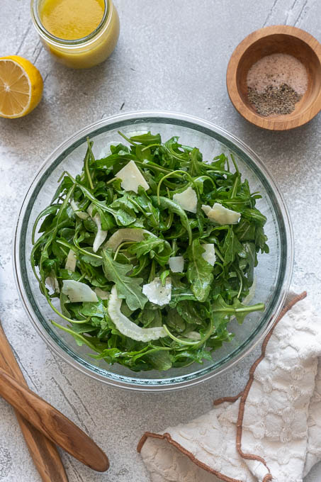 Fennel and arugula salad with parmesan tossed in a bowl.