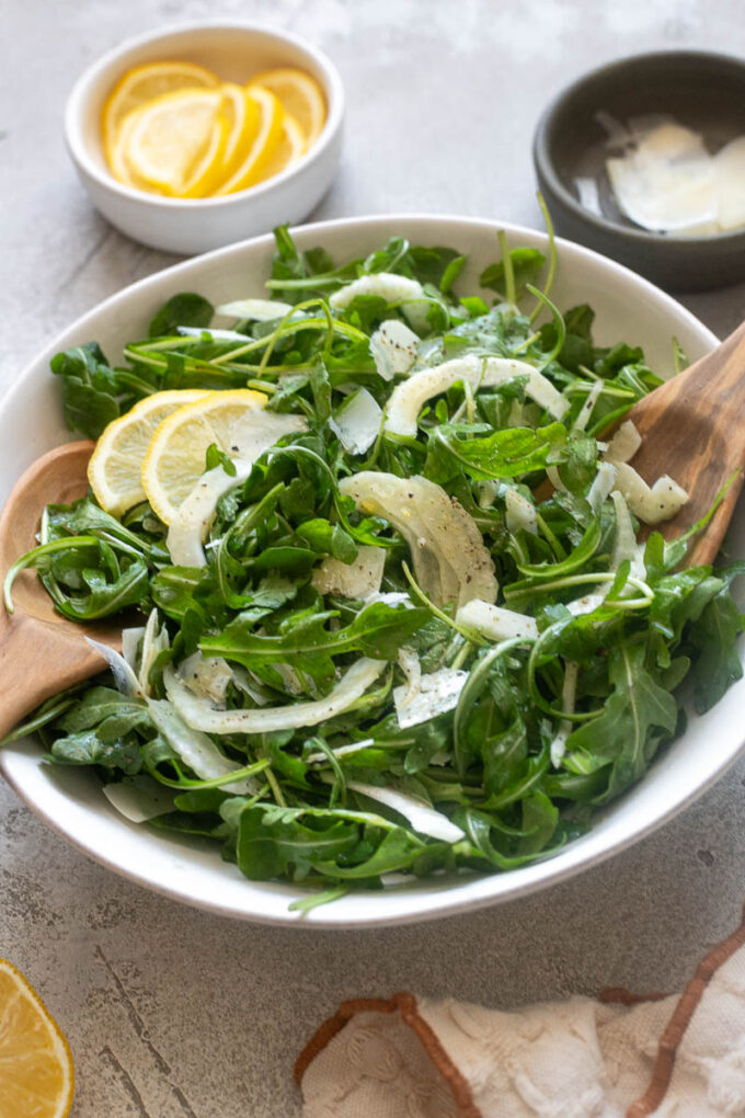 Simple fennel salad in a bowl with salad servers.