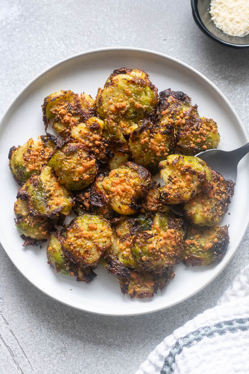 Smashed brussels sprouts on a plate with a serving spoon.