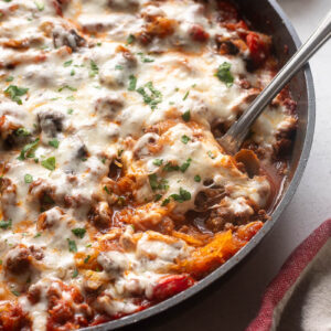 Spaghetti squash casserole in skillet with serving spoon digging in.