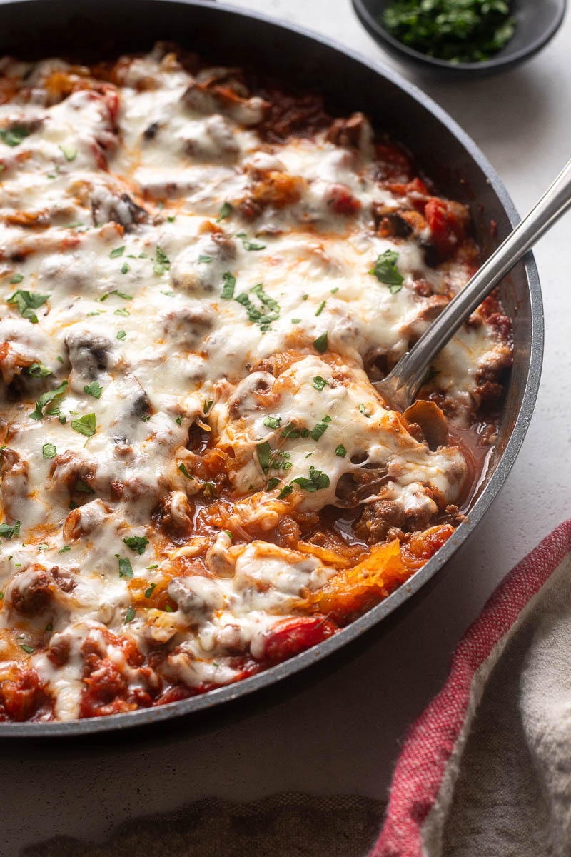 Spaghetti squash casserole in skillet with serving spoon digging in.