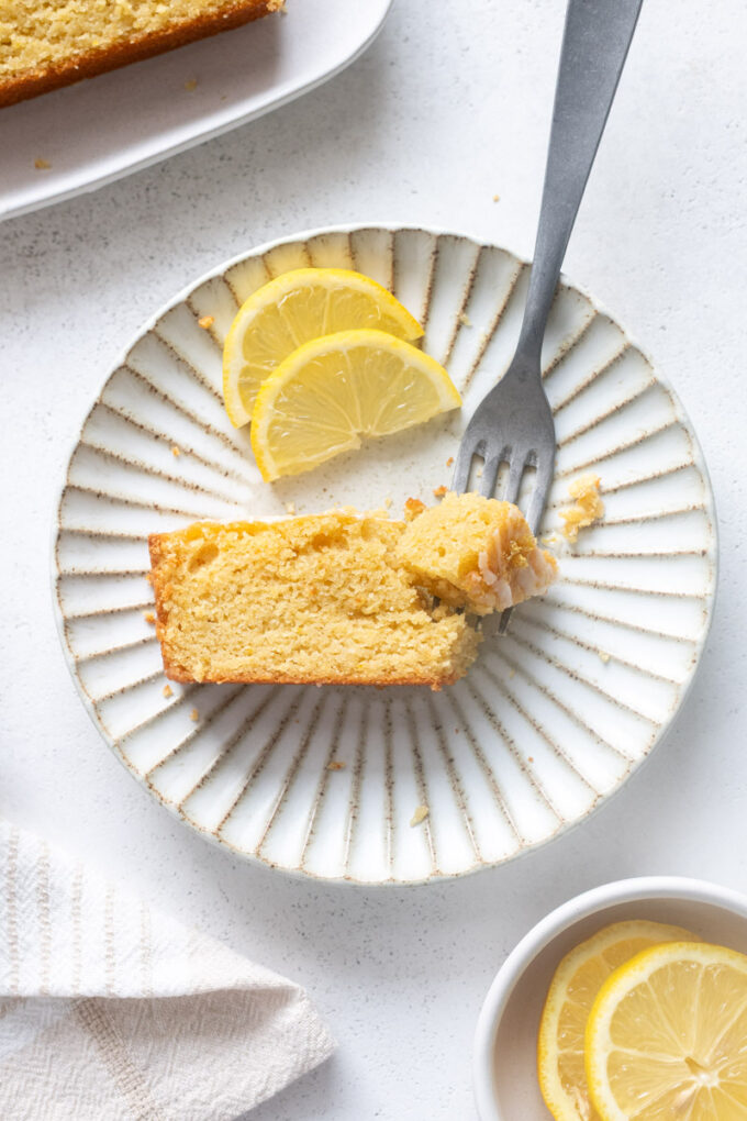 Slice of almond flour lemon loaf cake with glaze on a plate.