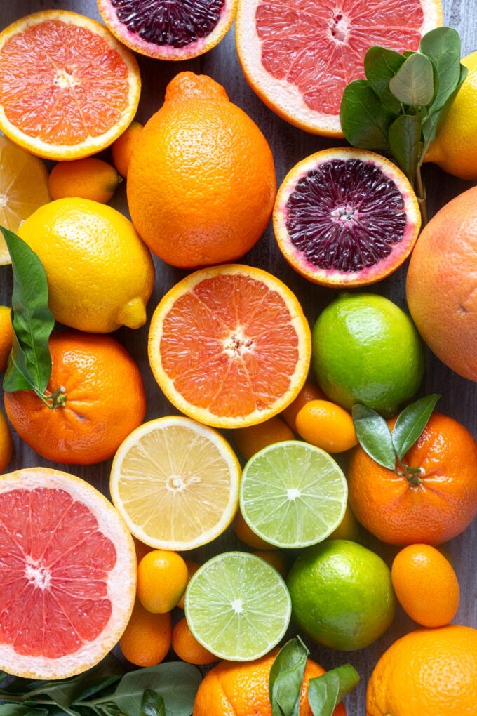 Assorted citrus fruits including oranges, lemons, limes and grapefruit arranged on a wooden surface.
