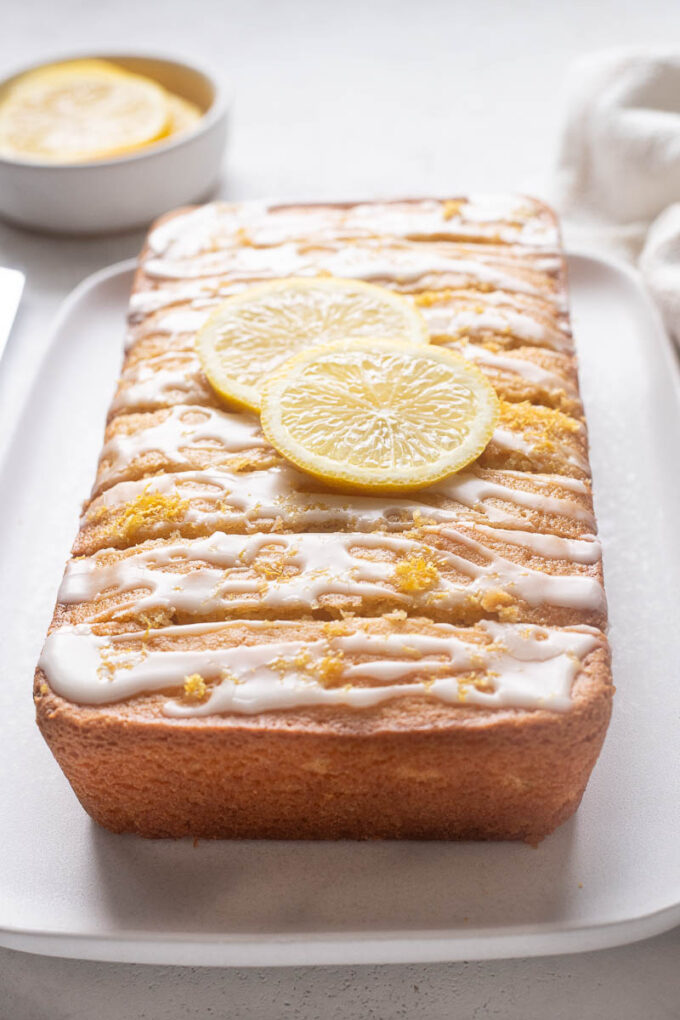 Gluten-free lemon loaf cake with lemon glaze and sliced lemons.