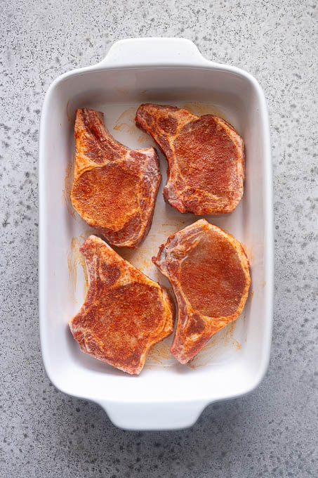 Seasoned pork chops in baking dish.
