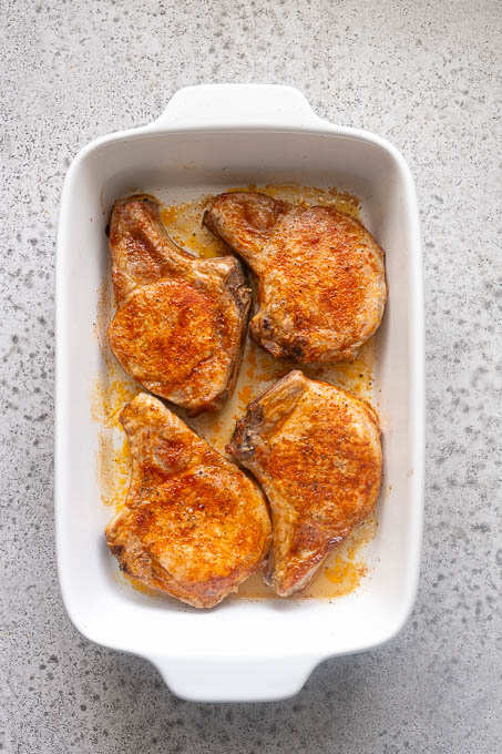 Baked bone-in pork chops in baking dish.
