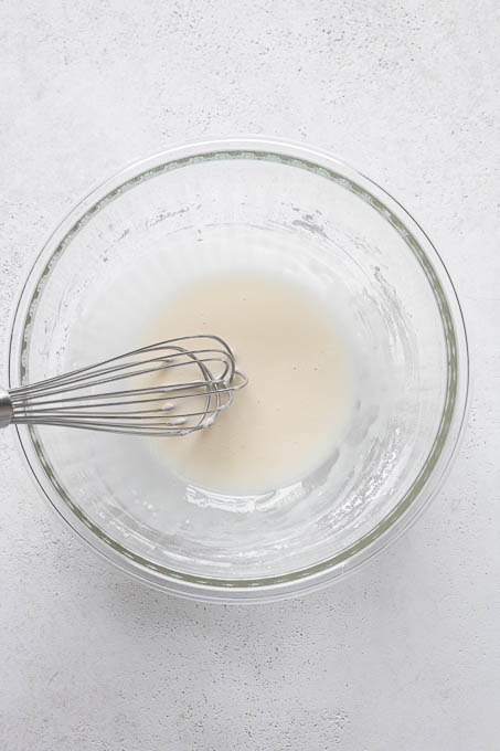 Glaze in mixing bowl for gluten-free lemon loaf.