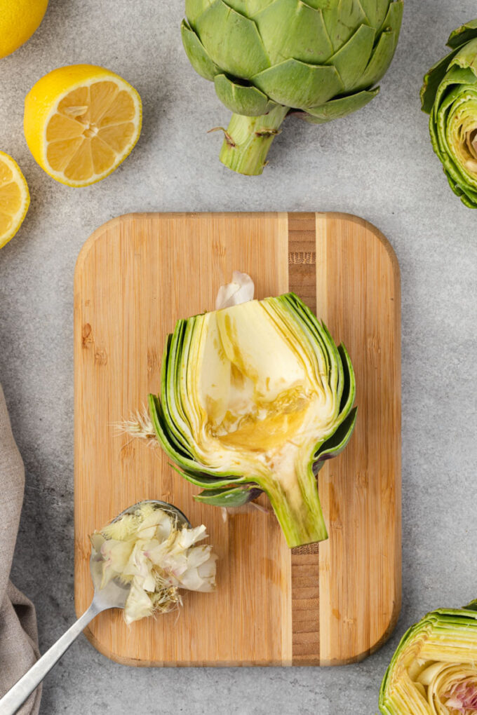 Scooping choke from artichoke with spoon.