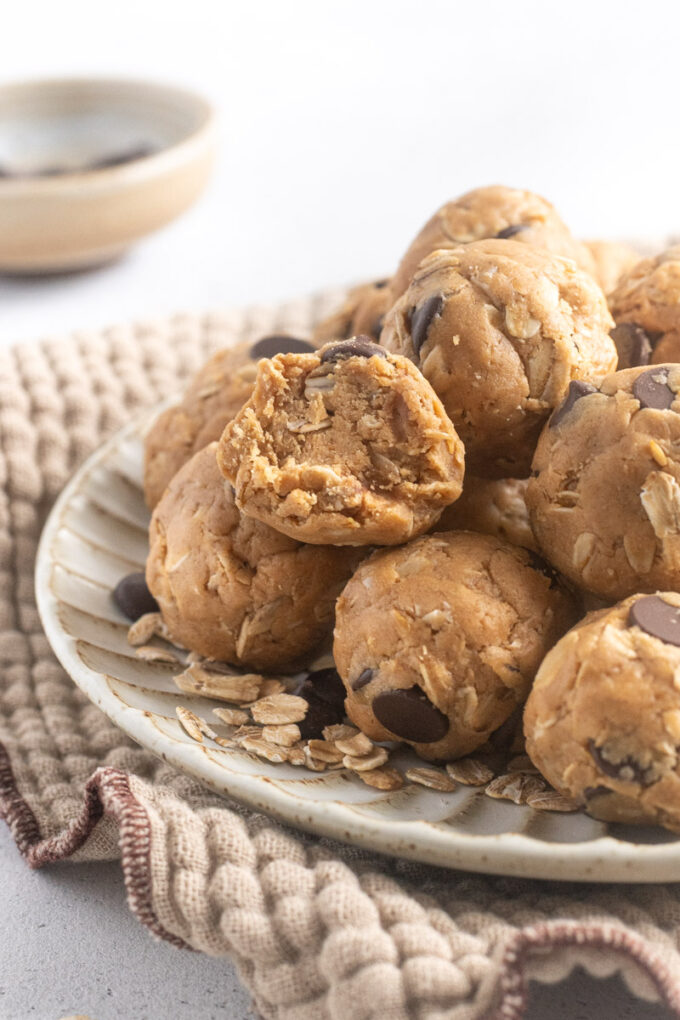 No-bake peanut butter protein balls on a plate with bite out of one ball.