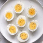 Air fryer hard boiled eggs cut in half with perfectly cooked yolks on a plate.
