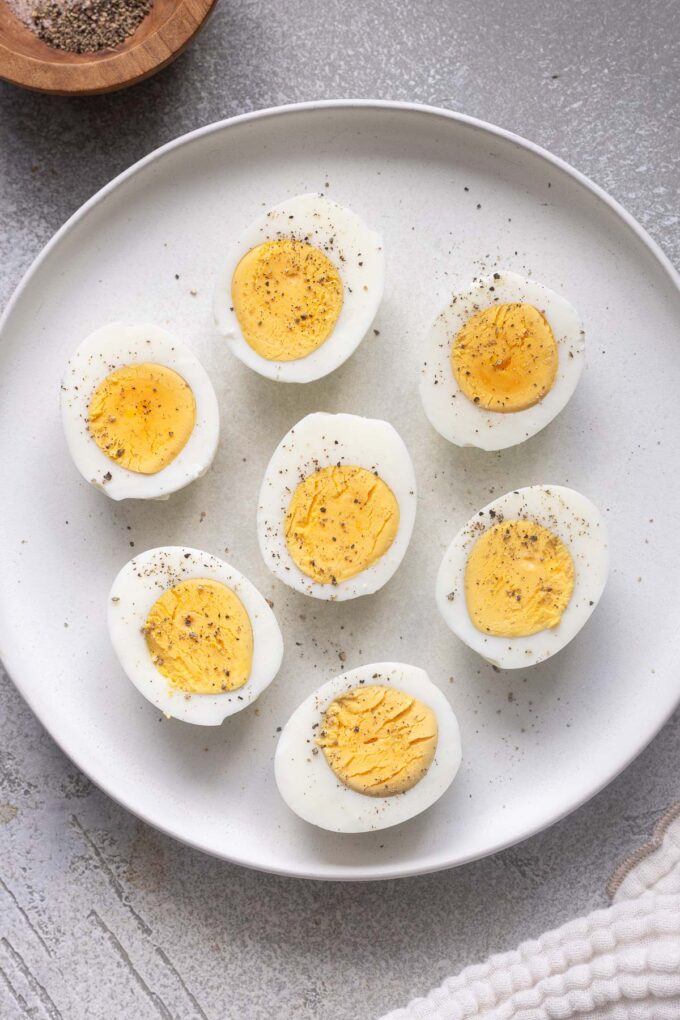 Air fryer hard boiled eggs cut in half with perfectly cooked yolks on a plate.