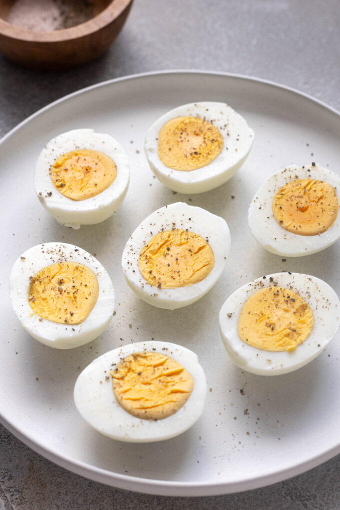 Halved air fryer hard boiled eggs on a plate with salt and pepper.