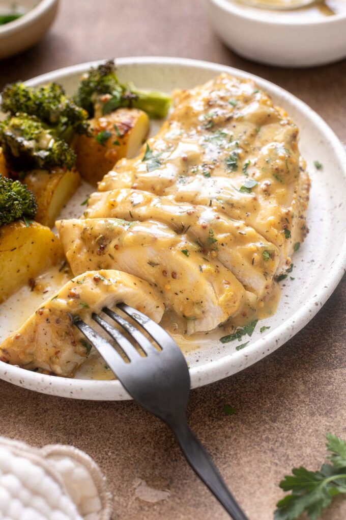Plated honey mustard chicken with roasted potatoes and broccoli.