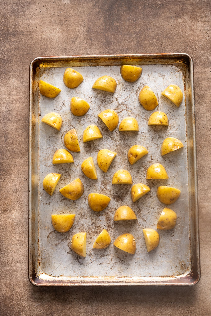 Halved baby gold potatoes on a baking sheet before roasting