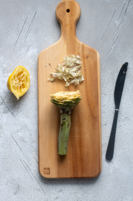 Pale yellow leaves cut off of artichoke and fuzzy choke removed.