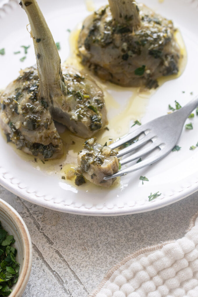 Roman artichokes, or Carciofi alla Romana, on a serving plate with slice removed.