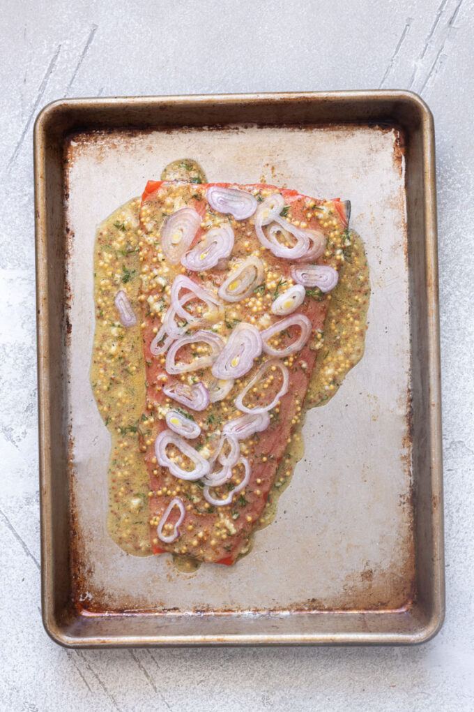 Wild salmon filet with citrus dijon sauce and shallots spread over the top.