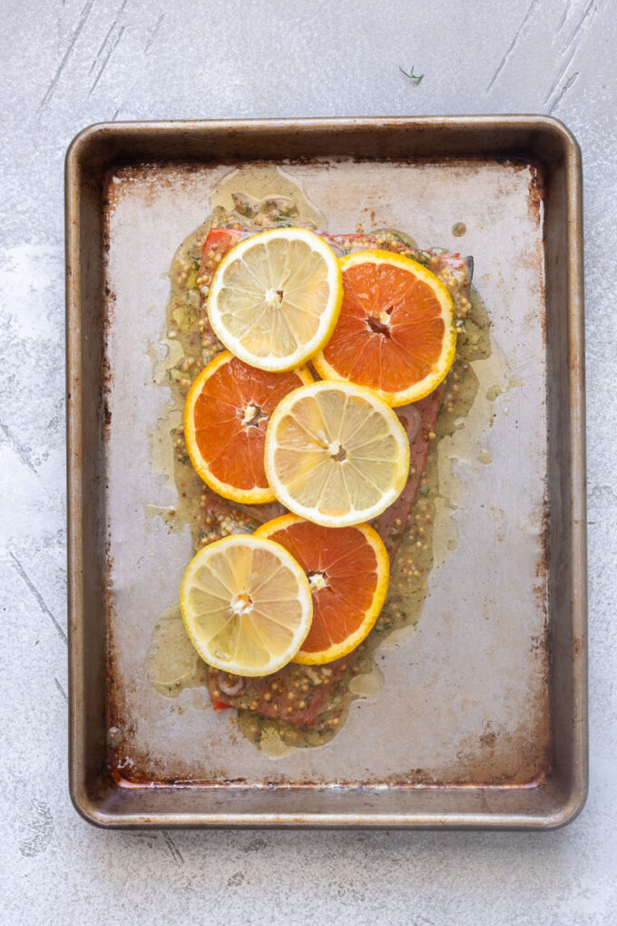 Salmon filet with citrus dijon sauce, sliced shallots and lemon and orange slices.