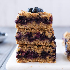 Stack of blueberry crumble bars with blueberries on top.