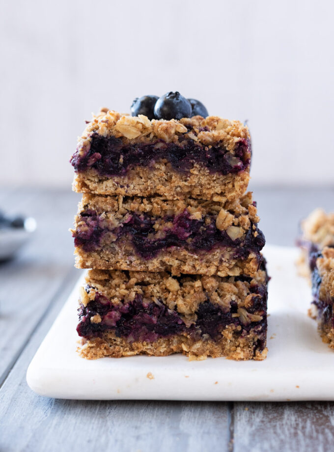 Stack of blueberry crumble bars with blueberries on top.