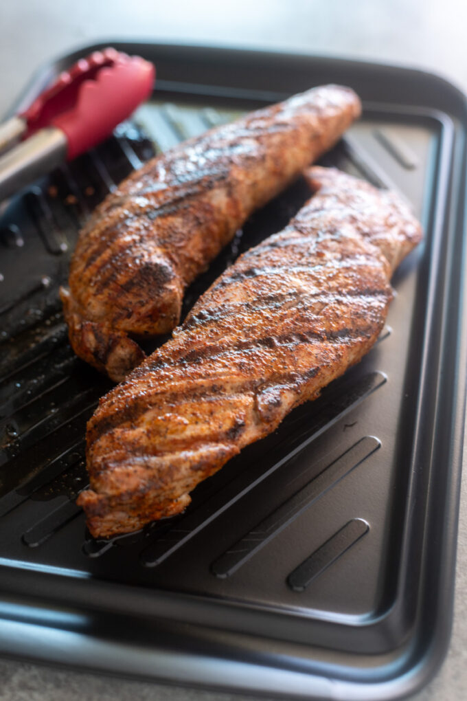 Spice rubbed grilled pork tenderloin on a cutting board.