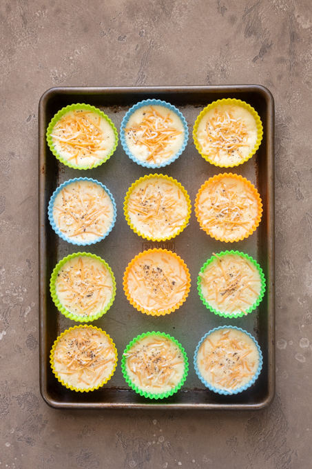 Blended egg and cottage cheese mixture in silicone muffin molds with grated cheese.