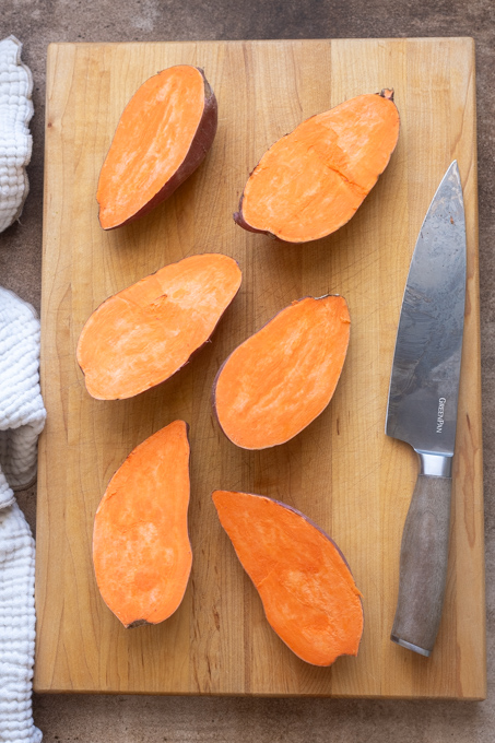Halved sweet potatoes on a cutting board.