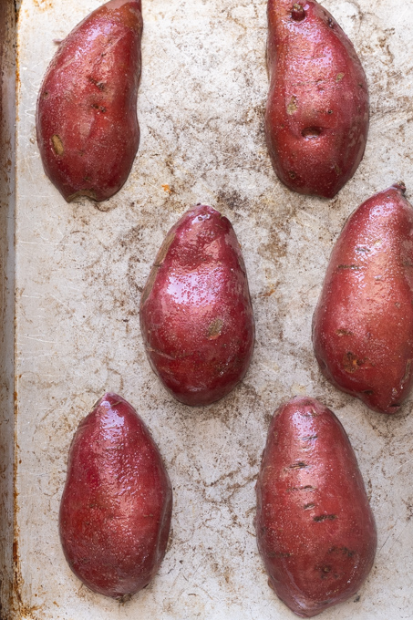 Sweet potatoes cut side down on baking sheet before roasting.
