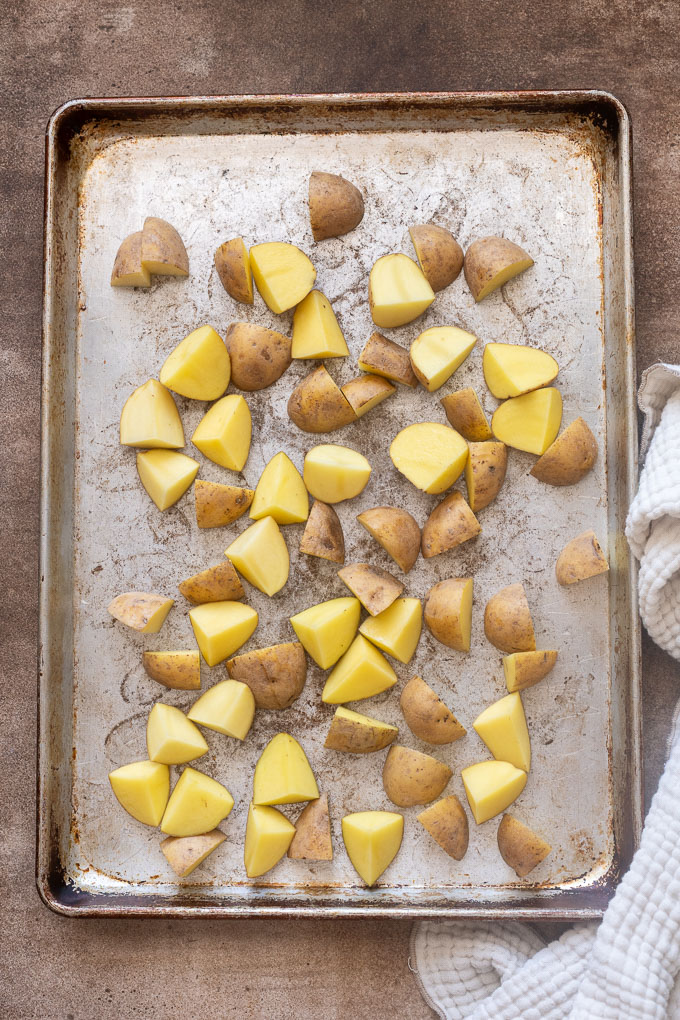 Quartered baby gold potatoes in a single layer on a baking sheet.