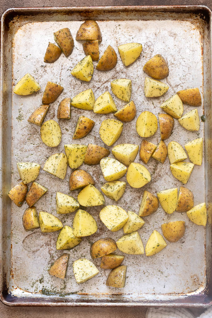 Baby gold potatoes coated with oil, ranch seasoning, salt and pepper on baking sheet.
