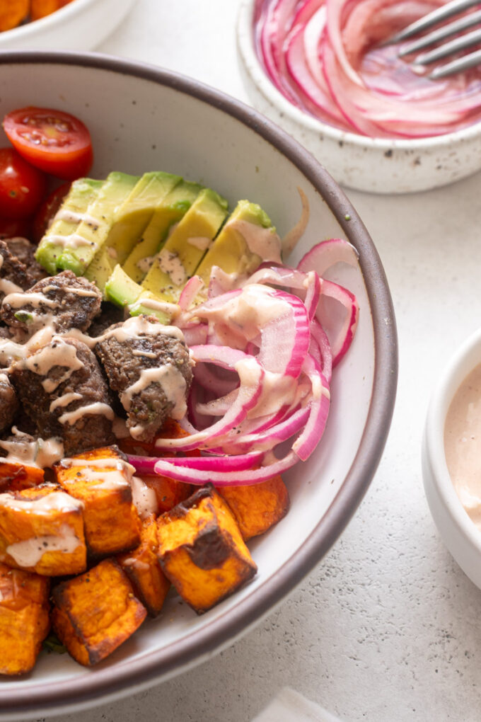 Pickled red onions in a burger bowl.