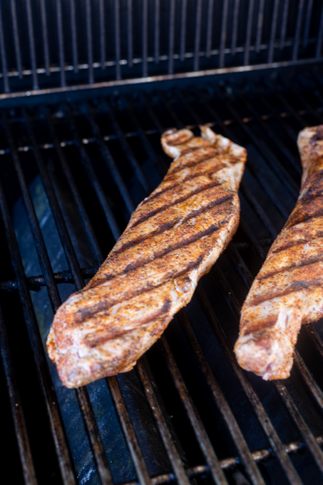 Pork tenderloins cooking on gas grill.