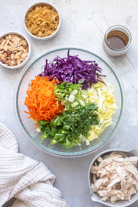 Chinese chicken salad ingredients sectioned in mixing bowl.