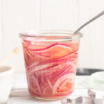 Quick pickled red onions in a jar with a fork buried in it.