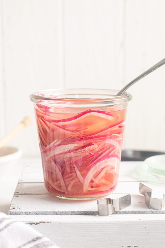 Quick pickled red onions in a jar with a fork buried in it.