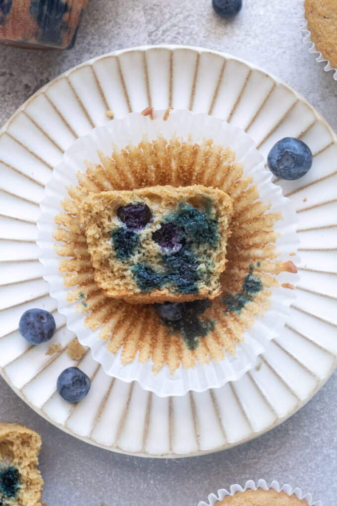 Blueberry oat flour muffin on a plate cut in half to expose tender crumb.
