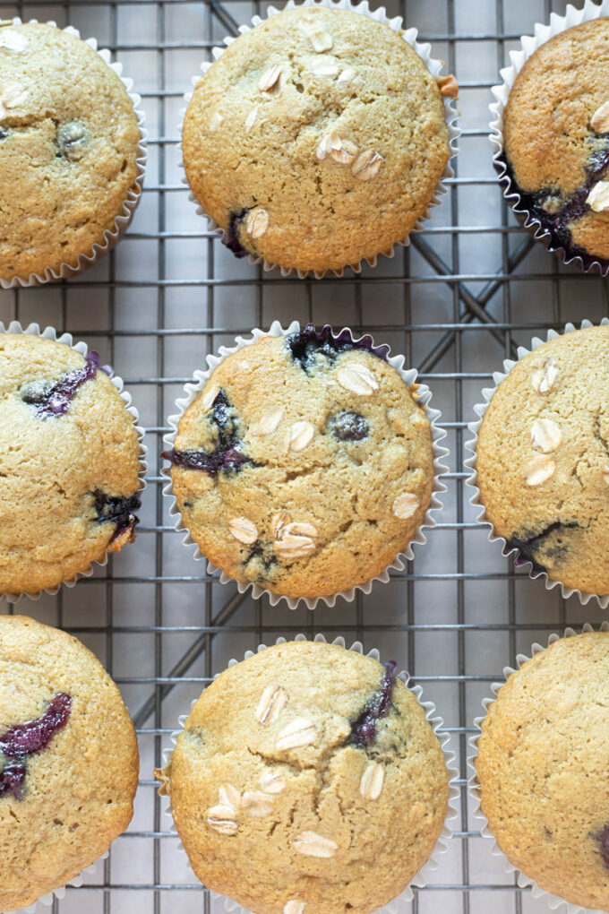 Blueberry oat muffins on a wire rack with rolled oats on top.