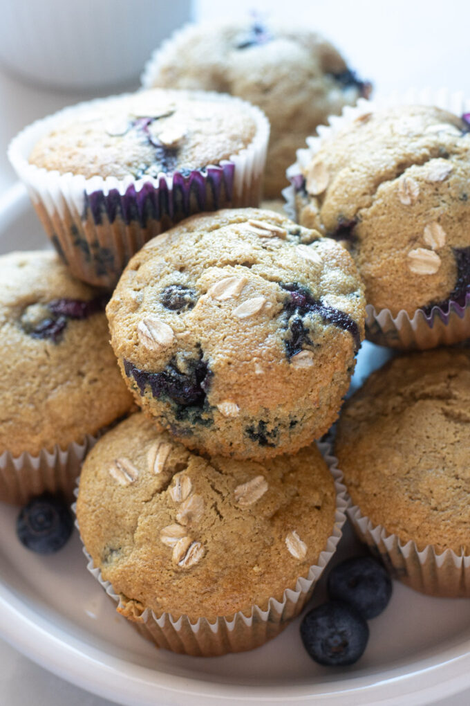 Blueberry oatmeal muffins piled on a plate.