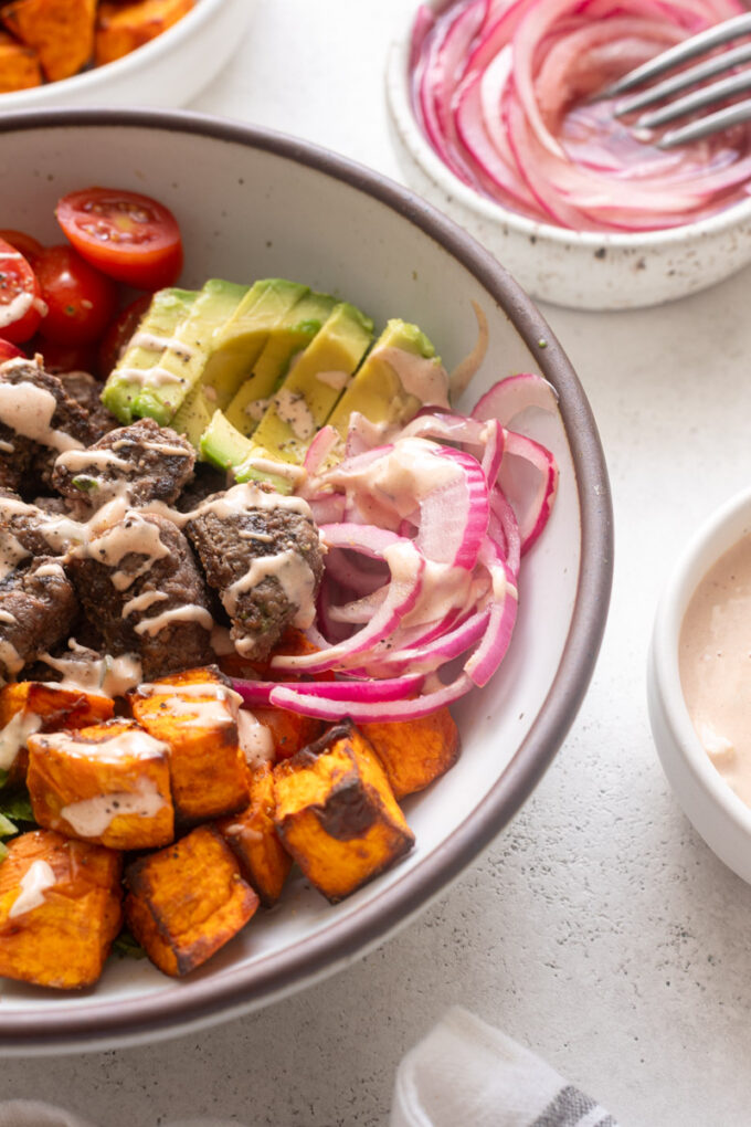 Close-up burger bowl with burger sauce, avocado and pickled onions.