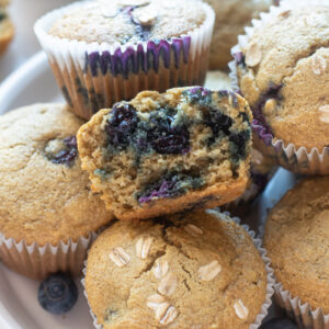 Blueberry oatmeal muffins on a plate with top muffin cut in half.
