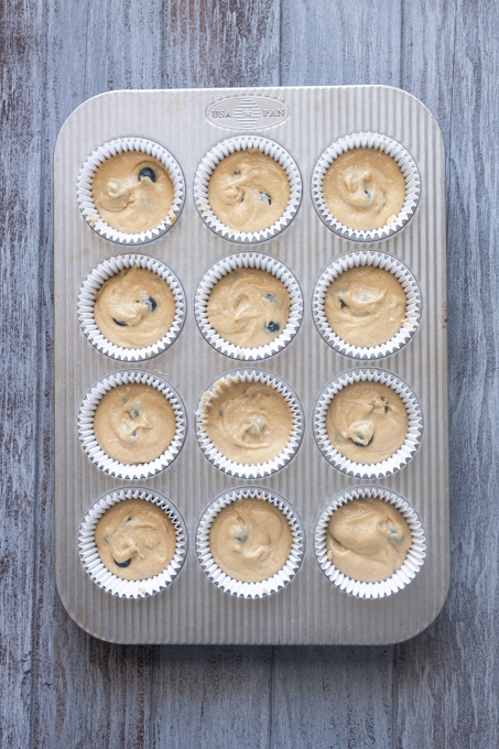 Blueberry muffins with oat flour batter in muffin pan before baking.