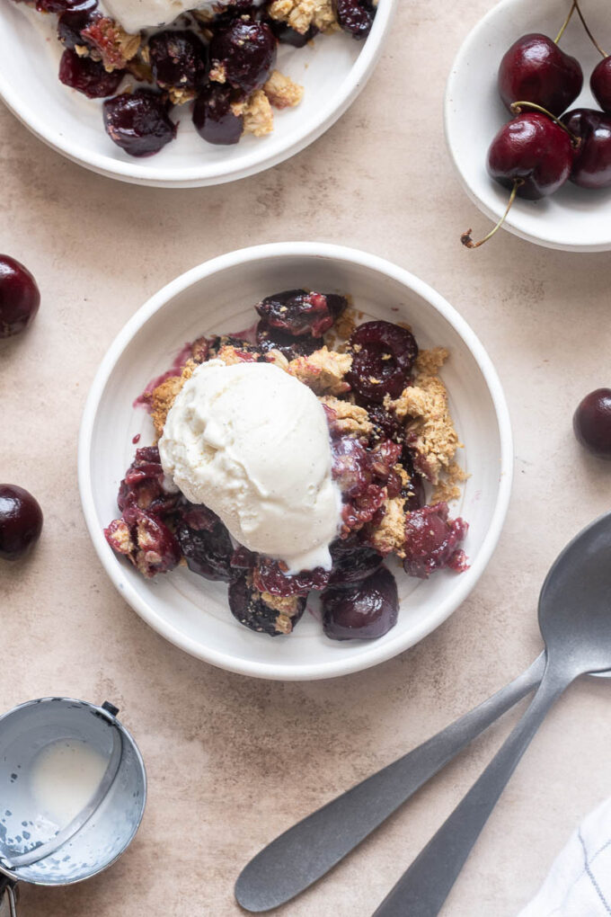Individual serving of fresh cherry crisp topped with vanilla ice cream.