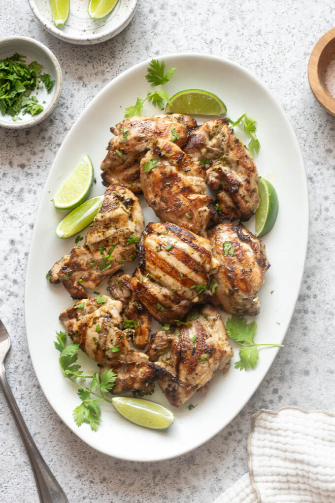 Overhead view of grilled cilantro lime chicken arranged on a white serving platter.