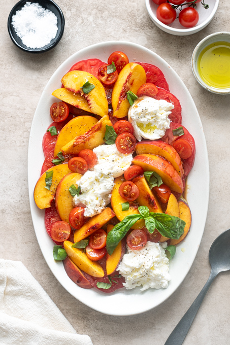 Finished tomato peach burrata salad with basil, olive oil and balsamic glaze.