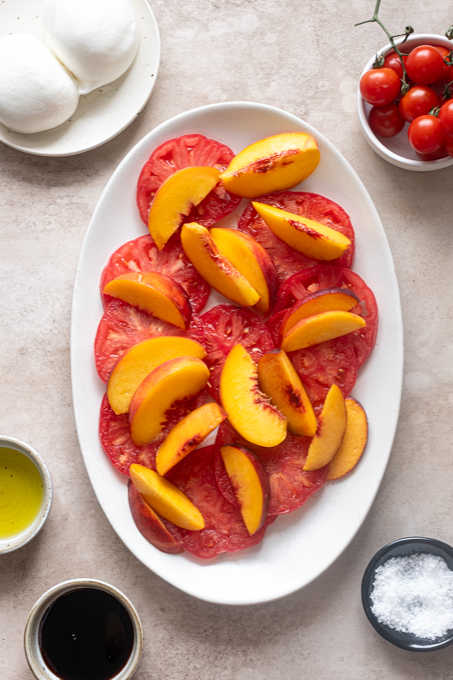 Heirloom tomatoes and peaches layered on a platter.