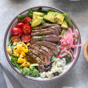 Grilled steak salad in bowl with chopped chives on top.